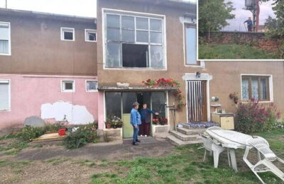 Locatarii unui bloc urcă pe o scară în casă, pentru că nu pot călca pe terenul pe care se află construcția