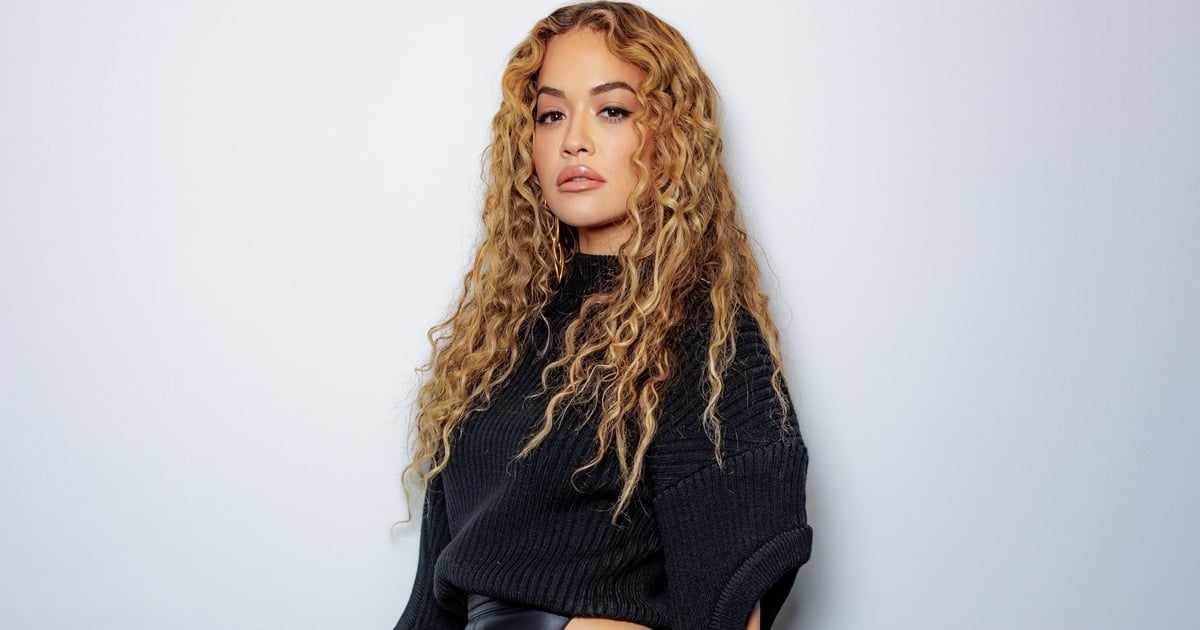 Rita Ora poartă o fustă neagră din piele decupată și un pulover negru