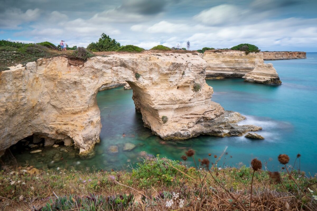 View of the Faraglioni di Saint Andrea rock formation with two arches on the shores of the Adriatic Sea in Italy.