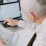 Pensionar completand formular pe laptop cu acte in
