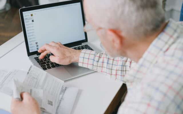 Pensionar completand formular pe laptop cu acte in