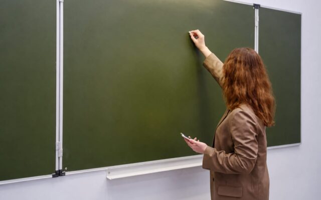 Cadru didactic scriind pe tablă