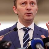 Bărbat gesticulând la mai multe microfoane