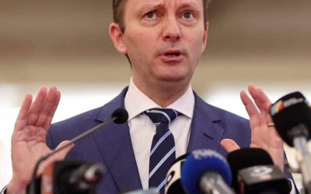 Bărbat gesticulând la mai multe microfoane