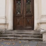 Intrarea unei clădiri istorice cu trepte de piatră și ușă masivă