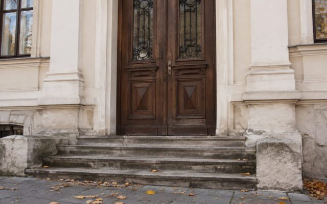 Intrarea unei clădiri istorice cu trepte de piatră și ușă masivă