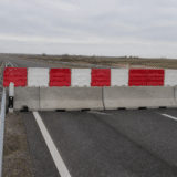 O imagine care prezintă un segment de autostradă blocat transversal de bariere din beton peste care sunt așezate elemente de plastic în culorile roșu și alb