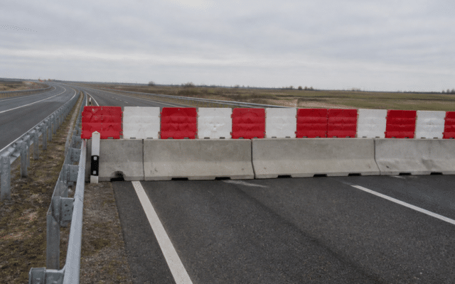 O imagine care prezintă un segment de autostradă blocat transversal de bariere din beton peste care sunt așezate elemente de plastic în culorile roșu și alb
