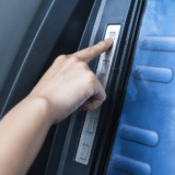 A person's hand pressing a button on an automated teller machine (ATM) displaying financial menu options