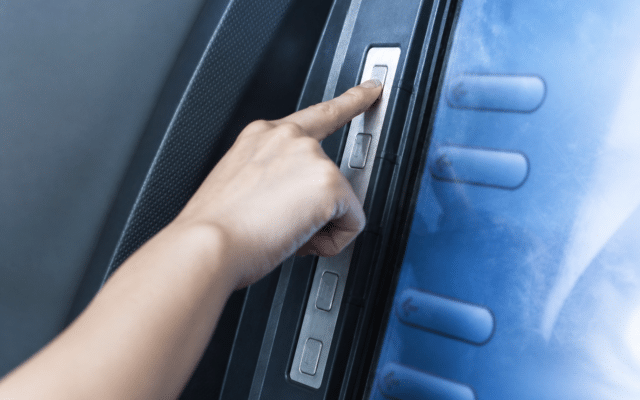 A person's hand pressing a button on an automated teller machine (ATM) displaying financial menu options