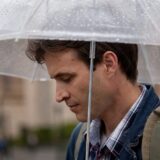 Bărbat sub umbrelă pe ploaie