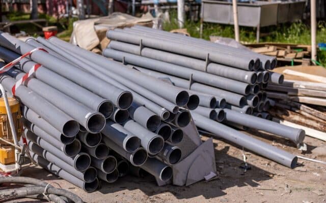 O stivă de țevi de plastic gri pentru canalizare sau alimentare cu apă depozitate pe un șantier