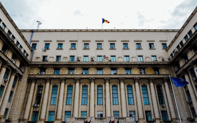 O vedere de jos în sus a Palatului Victoria, sediul Guvernului României, prezentând fațada principală cu coloane impunătoare și ferestre