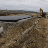 Un șantier de infrastructură rutieră într-o zonă deluroasă, sub un cer înnorat