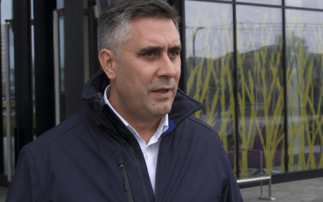 A man speaking in front of the modern architecture of the Brasov-Ghimbav International Airport terminal
