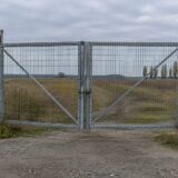 Poartă metalică și gard cu sârmă ghimpată la o frontieră externă