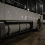 O fotografie de noapte care prezintă partea laterală a unui autobuz alb parcat