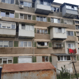 Exterior facade of an apartment building with various enclosed and modified balconies in poor condition