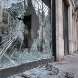 Vitrină distrusă și pietre pe trotuar