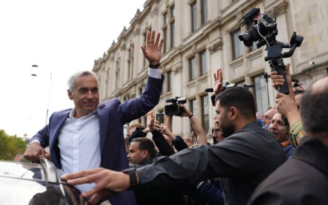 Bărbat salutând mulțimea de jurnaliști
