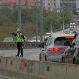 A traffic police officer directing traffic on a busy road with multiple cars and barriers