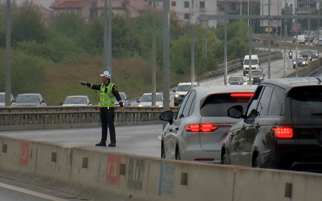 A traffic police officer directing traffic on a busy road with multiple cars and barriers