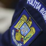 Detaliu al uniformei unui polițist, concentrat pe emblema brodată de pe braț care reprezintă stema României și inscripția instituției