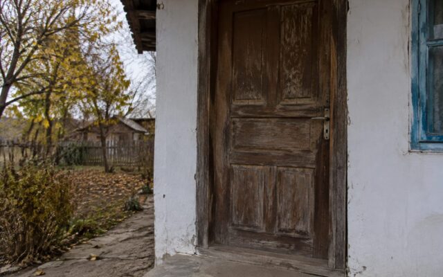 Ușa unei locuințe modeste din mediul rural într-un decor de toamnă