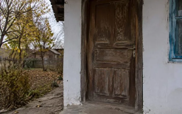 Ușa unei locuințe modeste din mediul rural într-un decor de toamnă